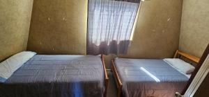 two beds in a small room with a window at Casa Castro Villa in Castro