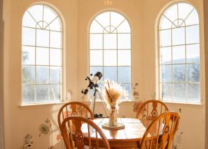 a dining room with a table and chairs and windows at Heaven Heights - HotTub, Pet Friendly, EV Outlet, Pool Table, Game Room, BBQ, FirePit, Library in Oakhurst