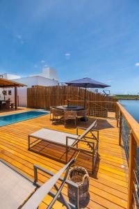 a wooden deck with a table and an umbrella at Bahia Soul - Casa Ayla - Barra Grande - Península de Maraú in Marau