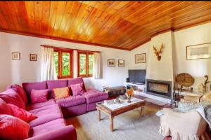 ein Wohnzimmer mit einem lila Sofa und einer Holzdecke in der Unterkunft Casa Soutinho - Gerês in Ventosa
