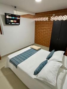 a bedroom with a bed with pillows and a tv at Aparta hotel Montes in Medellín