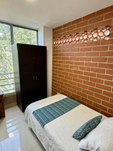 メデジンにあるAparta hotel Montesのレンガの壁とベッドが備わるベッドルーム1室が備わります。