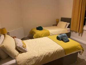 a bedroom with two beds with yellow sheets at Papa Jim's Cottage in Dirleton