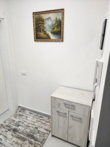 a painting hanging on a white wall with a cabinet at Apartmani Nikmil Vrnjačka Banja in Vrnjci