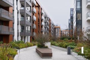 a bench in front of a building with a garden at Penthouse Brabank Japandi Luxury Sauna, Fitness & Parking by Grandview in Gdańsk