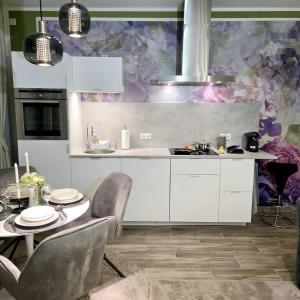 a kitchen with white cabinets and a table with chairs at City APART - FeWo Klimaanlage Whirpool Panoramafenster 5 Personen Kulturdenkmal Dessau-Roßlau in Dessau