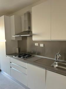 a kitchen with white cabinets and a stove top oven at Appartamento Astri EUR in Rome