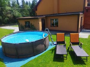 a pool with two chairs and a swing in a yard at Ubytování Pod statkem in Tichá