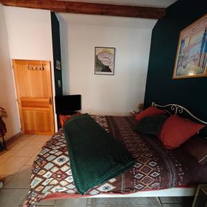 a bedroom with a bed with a green blanket on it at Le P'tit gîte in Saint-Privat