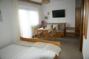 Schlafzimmer mit einem Bett, einem Tisch und einem TV in der Unterkunft Pension Andrea in Sankt Peter im Sulmtal
