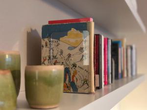 a shelf with two books and a candle and a candle at Design Apartment - Self-Check-In - Maschsee in Hannover +21 photos