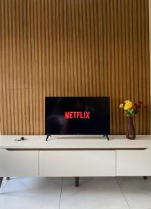 a tv sitting on top of a white table at Aconchego em Campo Grande - Guaratiba in Rio de Janeiro
