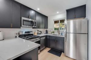 a kitchen with black cabinets and a stainless steel refrigerator at Brand New Apt W Parking Blocks From Downtown- A in Sunnyvale