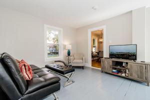 a living room with a black leather couch and a flat screen tv at The Maisonette by Corbitt Hospitality in Annapolis Royal