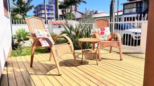 three wicker chairs and a table on a deck at Casa da Praia Pousada in Torres