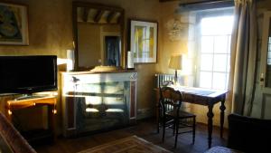 a living room with a fireplace and a table and a television at Les Douves in Onzain