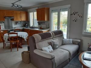 a living room with a couch and a kitchen at Maison de campagne in Plémet