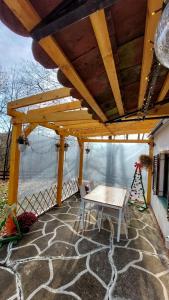 a wooden pergola with a table on a patio at Vikendica WoodNook Kosmaj - Šumski kutak in Sopot