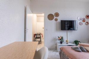 a living room with a bed and a television on a wall at Grand T1 confortable - Calme et Proche de Paris in Montreuil