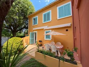 a house with a table and chairs and an umbrella at Résidence LO MONACO Haut de villa, Appartements et Studios in San-Nicolao
