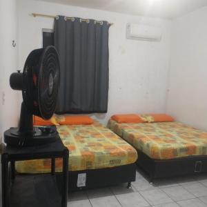 a room with two beds and a fan on a table at Casarão Farol da Marise Sol in Belém