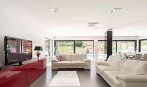 a living room with white furniture and a tv at Amazing Villa in Douro Valley - Pool in Espinhosa