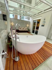 a bathroom with a large white tub on a wooden floor at Apartamento Exclusivo a 600m da Praia de Palmas Piscina Banheira de Imersão aquecida rede in Governador Celso Ramos