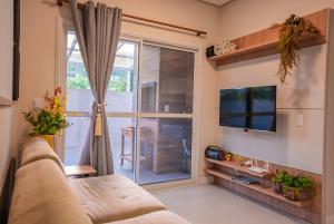 a living room with a couch and a large window at Apartamento Exclusivo a 600m da Praia de Palmas Piscina Banheira de Imersão aquecida rede in Governador Celso Ramos