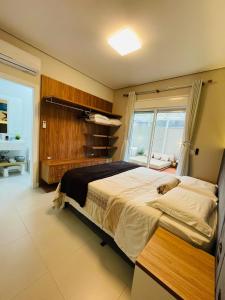 a bedroom with a large bed and a window at Apartamento Exclusivo a 600m da Praia de Palmas Piscina Banheira de Imersão aquecida rede in Governador Celso Ramos