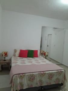 una camera da letto con un letto con cuscini rossi e verdi di Casa Marisol Maresias a São Sebastião