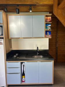 a kitchen with white cabinets and a sink at Pousada Chalé Flor de Hibisco 3 in Penha