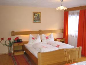a bedroom with a bed with white sheets and red curtains at Haus Cilli in Virgen