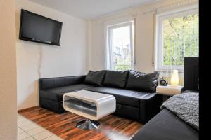 a living room with a black leather couch and a tv at Traumwohnung Stuttgart in Stuttgart