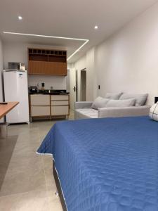 a living room with a blue bed and a kitchen at Juca Studio Botafogo in Rio de Janeiro