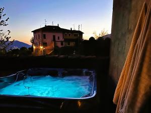 a hot tub in a yard with a house in the background at La Rungia - Private Jacuzzi, Free Parking & EV Wallbox in Bosco Luganese