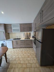 a kitchen with wooden cabinets and a black refrigerator at Maisonnette in Villar-Saint-Pancrace