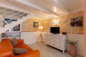 sala de estar con sofá naranja y TV en Sassi SediciDiciotto, en Matera