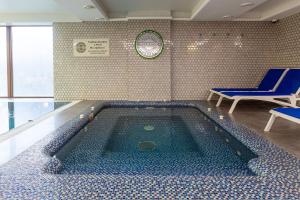a swimming pool in a room with blue chairs and a clock at MARION SPA Hotel in Bukovel