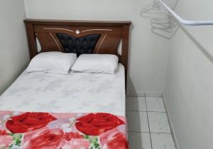 a bed with two red roses on it at Lara 1 in Vitória da Conquista