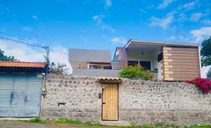 a house behind a stone wall with a wooden door at Rincon Arrayán in Otavalo