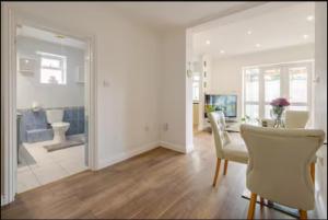 a living room with a table and chairs and a bathroom at Spacious 2BDR Apartment, WIFI+ Great TV in Romford