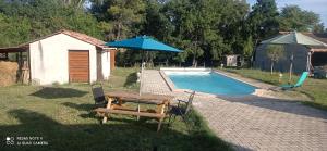 a picnic table and an umbrella next to a pool at Tiny house aux portes des cevennes in Saint-Privat-des-Vieux
