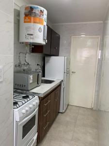 a kitchen with a stove and a white refrigerator at DEPARTAMENTO DOS AMBIENTES APTO 4 Personas in Mar del Plata +2 photos