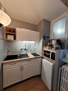 Una cocina con gabinetes blancos y un horno de estufa. en L'Edelweiss, en La Bourboule