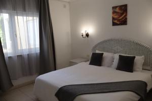 ein Schlafzimmer mit einem weißen Bett mit schwarzen Kissen und einem Fenster in der Unterkunft Chayofa Escape Relax and Enjoy in Chayofa + 16 Fotos