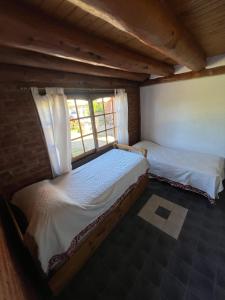 two beds in a room with a window at Aldea Bolsón in El Bolsón