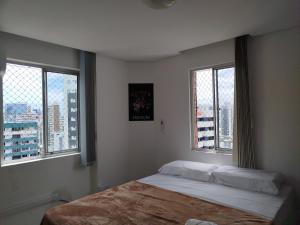 a bedroom with a bed and two windows at Cobertura Duplex Vista do Mar in Recife +60 photos