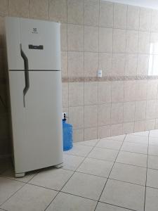Una nevera blanca en una habitación con una pared de azulejos. en AP Varanda do Mar - Rio das Ostras, en Rio das Ostras