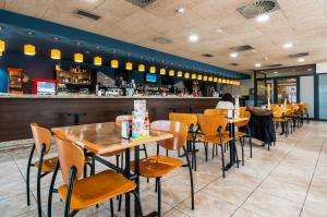 Un restaurante con mesas y sillas y un bar. en ibis Styles Pamplona Noain, en Noáin