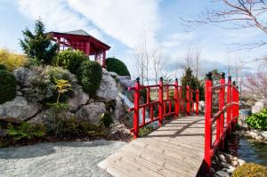 un puente de madera sobre un río con una valla roja en ibis Styles Pamplona Noain, en Noáin